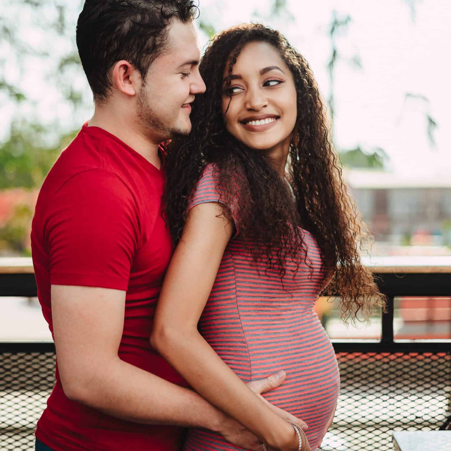 A man hugs his partner's pregnant belly. Intimacy is an important tool for labor.